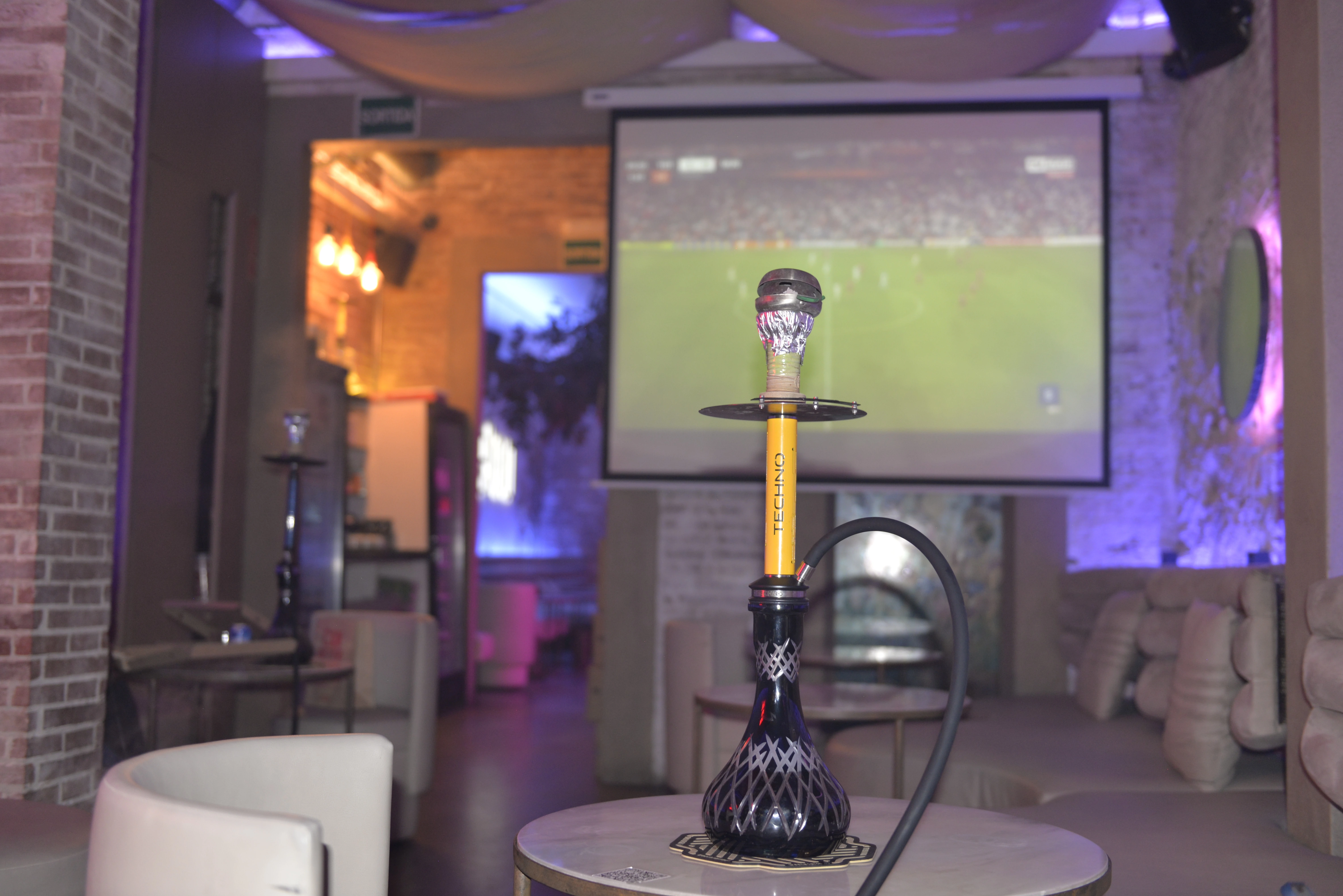 Ambiente del hookah lounge Mellow con sofás cómodos y pantalla para eventos deportivos